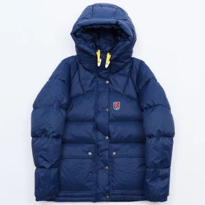 Blå dunjacka från Fjällräven Expedition  - Säljer en blå dunjacka från Fjällräven i bra skick. Ny pris: 7999 kr, då det inte är den ”vanliga” modellen. Säljer för 3500 kr pågrund av att den är lappad på baksidan av ena ärmen, inget som syns dock. Jackan har en mysig huva och praktiska fickor med knappar. Perfekt för kalla vinterdagar. Några små tecken på användning finns, men inget som påverkar funktionen. Priset kan diskuteras vid snabb affär. Kan hämtas upp i Täby, men kan även postas. STÅR INTE FÖR POSTENS SLARV. 