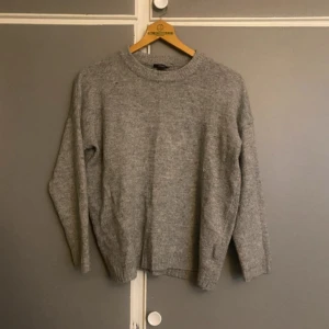 Grå stickad tröja  - Mysig grå stickad tröja från H&M i bra skick. Perfekt för höst och vinter med sin varma och bekväma design. Tröjan har långa ärmar och en klassisk rund halsringning. Passar perfekt till både jeans och kjol för en avslappnad look.
