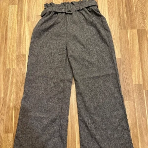 Grå byxor med bälte - Snygga grå byxor i loose fit med hög midja. De har ett matchande bälte i midjan som ger en extra touch och går att ha utan! Från Shein i storlek L i nyskick!