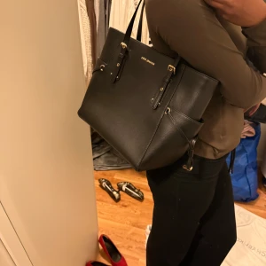  Michael Kors - Säljer en elegant svart axelväska från Michael Kors i mycket bra skick. Väskan är tillverkad i skinn och har snygga gulddetaljer. Perfekt för både vardag och fest! 🖤helt ny väska 