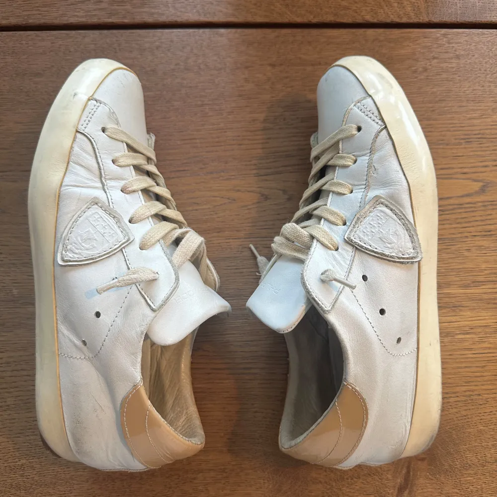 Säljer ett par vita sneakers från Philippe Model i bra skick. Skorna har en klassisk design med beige detaljer och snörning. Perfekta för vardagsbruk och ger en stilren look. Sulorna är i gott skick med tydlig logga under. Passar 40/41 i storleken . Skor.