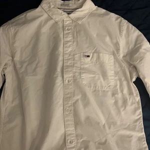 Vit skjorta från Tommy hillfiger - Säljer en klassisk vit skjorta från Tommy hillfiger i storlek L. Skjortan har en regular fit och är tillverkad i bomull. Den har snygga knappar med Tommy hillfiger logga. Perfekt för både vardag och fest! 🕺