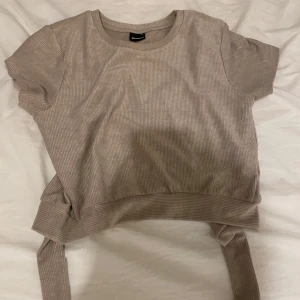 Beige ribbad topp med öppen rygg - Fin beige tröja med öppen rygg och band att knyta ihop den med det är stl M men tycker personligen den sitter som en S-Xs då jag är väldigt smal