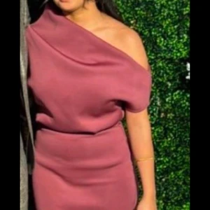 Vinröd oneshoulder klänning - Snygg vinröd oneshoulder klänning i ett elegant och stilrent snitt. Perfekt för festliga tillfällen. Klänningen har en tight passform som framhäver figuren och är gjord i ett mjukt material för extra komfort.