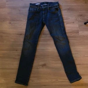 Blå jeans från Replay - Säljer ett par snygga blå jeans från Replay i modellen Anbass. De är i bra skick och har en slim passform som sitter perfekt. Jeansen har klassiska fyra fickor och en dragkedja med knapp. Perfekta för både vardag och fest! Hör av er vid fler frågor och bilder!