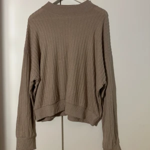 Beige ribbad tröja - Säljer en supermysig beige ribbad tröja. Den har en loose passform och långa ärmar, perfekt för höst och vinter. Tröjan är i bra skick och passar till alla tillfällen när du vill vara både bekväm och stilren. Perfekt att matcha med jeans eller kjol!