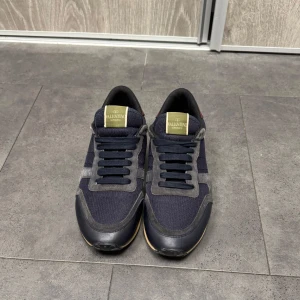 Valentino Rockrunners - Säljer ett par snygga Valentino sneakers i mörkblått och grått.  Har en sjukt bekväm sula. Perfekta för både vardag och fest! Skorna är i mycket bra skick och har en stilren look med snörning. Kontakta mig för minsta lilla funderingar!