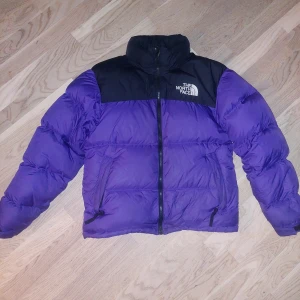 Lila pufferjacka från The North Face - Säljer en snygg lila pufferjacka från The North Face i storlek herr XS. Jackan är perfekt för kalla dagar med sin tjocka vaddering. Perfekt för vintern!