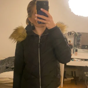 Svart vinterjacka med pälsdetaljer - Säljer en snygg svart vinterjacka från Svea med mysig päls på huvan. Jackan har dragkedja framtill och är perfekt för kalla dagar. Den är i mycket bra skick och passar perfekt för vintern. Storleken är dam S.