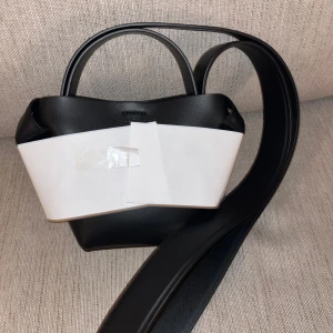  Acne Studios Musubi micro tote  - Säljer en stilren svart handväska från Acne Studios i modellen Musubi micro tote. Väskan har en minimalistisk design med en elegant axelrem. Perfekt för både vardag och fest! Kommer med original dustbag och kort kvitto finns bara o fråga. Jag fick väskan som en present och vill sälja den då jag redan har många svarta väskor väskan säljs för 8000kr på acne studios egna hemsida 