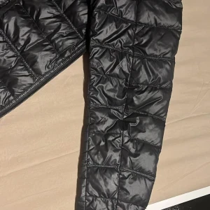 Svart EA7 jacka - Säljer en snygg svart EA7 jacka i mycket bra skick. Den har en dragkedja framtill och är perfekt för höst och vår. Jackan är långärmad och har en stilren design som passar till det mesta. Perfekt för dig som vill hålla stilen när det blir lite kyligare ute. 