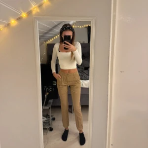 chinos/ byxor  - Säljer ett par snygga beige chinos i normal passform.  Storlek XS. Pris 55:- De är perfekta för både vardag och lite mer uppklädda tillfällen. Byxorna har en hög midja och är gjorda i ett bekvämt bomullsmaterial. De har praktiska fickor och en stilren design. Passar perfekt till en enkel topp eller skjorta!