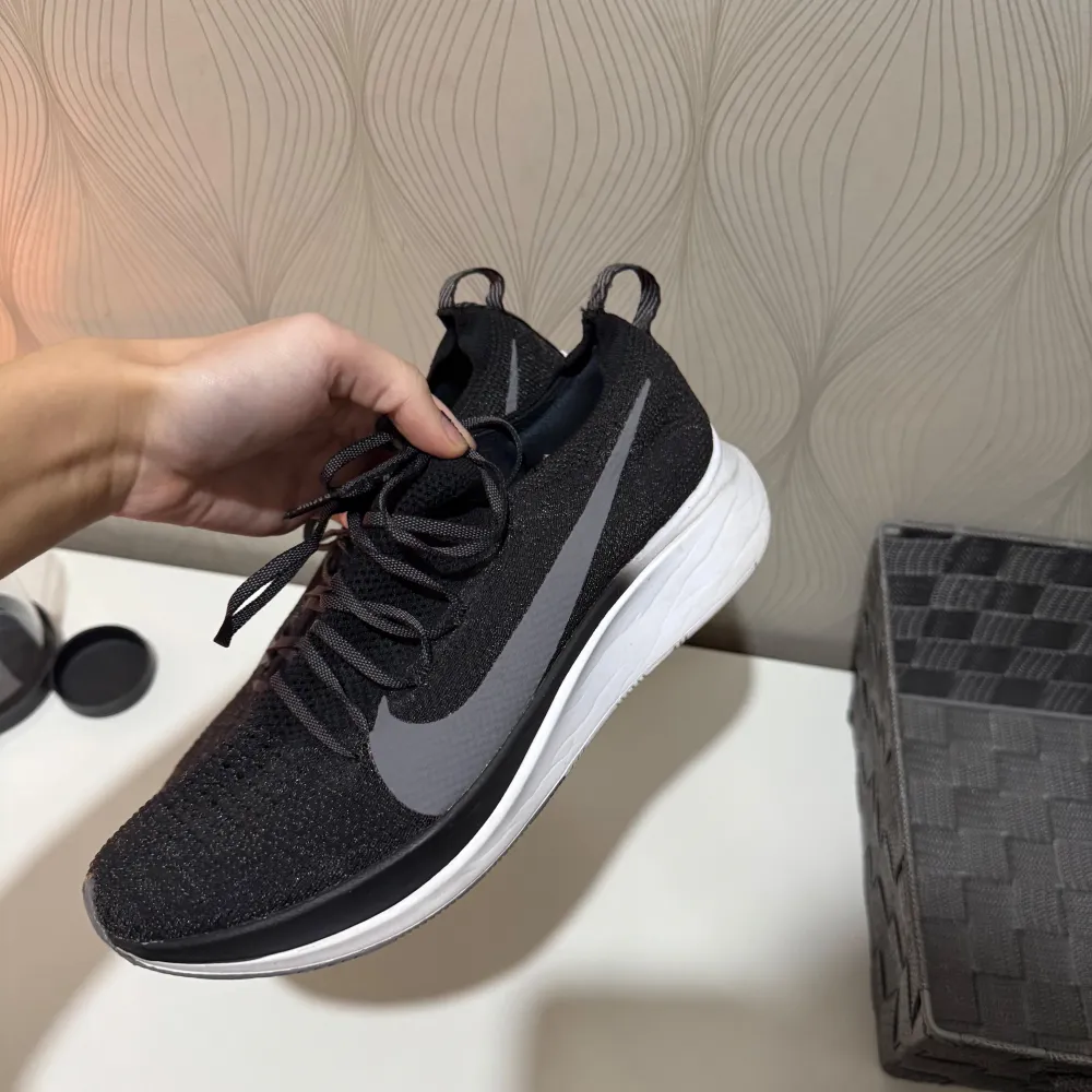 Säljer ett par snygga svarta Nike sneakers i mycket bra skick. De har en stilren design med grå swoosh och vit sula. Perfekta för både träning och vardag. Skorna har snörning och är gjorda i ett bekvämt syntetmaterial.. Skor.