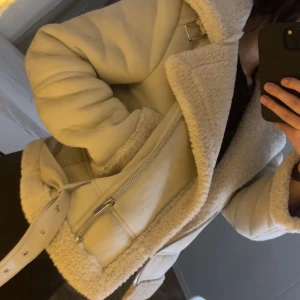 Beige jacka med teddyfoder - Säljer en supermysig beige jacka med teddyfoder. Den har en dragkedja framtill och ett bälte. Perfekt för kyliga dagar och ger en snygg look med sina detaljerade fickor och krage. Kan sälja den för billigare pris vill bli av med en, kom med pris förslag 😊