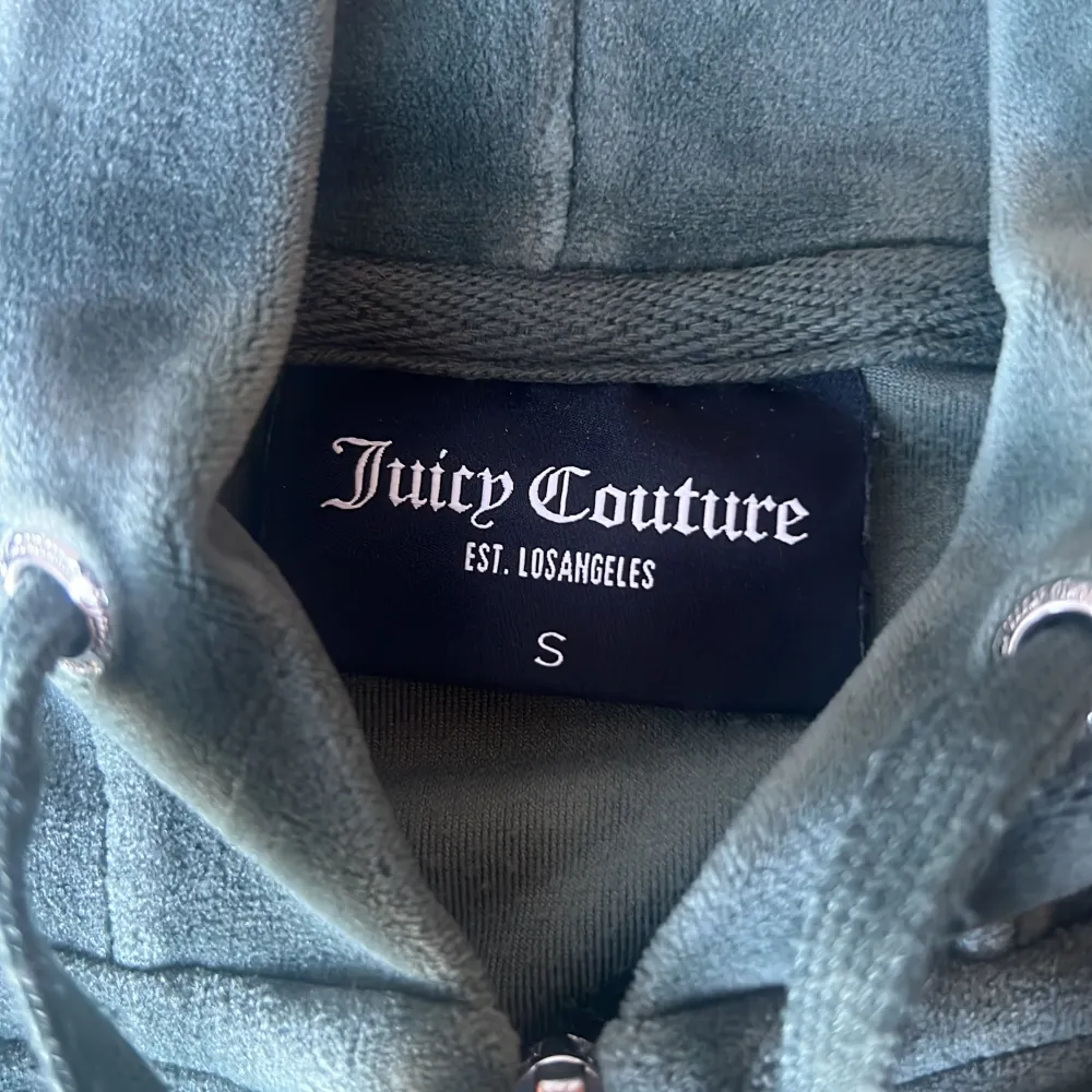 Säljer en supermjuk och snygg grön hoodie från Juicy Couture. Den har en dragkedja framtill och en praktisk huva. Perfekt för en avslappnad stil eller mysiga dagar hemma. Den är i bra skick och redo för en ny ägare!. Jackor.