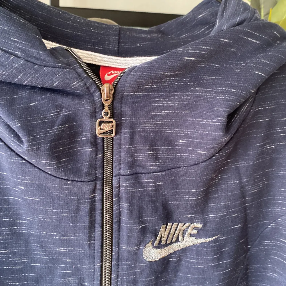 Säljer en snygg mörkblå hoodie från Nike med dragkedja och huva. Den har ett diskret mönster och Nike-loggan broderad på bröstet. Perfekt för en avslappnad stil!. Jackor.