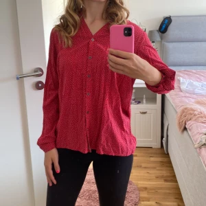 Röd prickig blus - Säljer en superfin röd blus med små vita prickar. Den har långa ärmar och knappar hela vägen ner. Perfekt för både vardag och fest! 💃 Armarna kan både bli trekvart och hela vägen. 