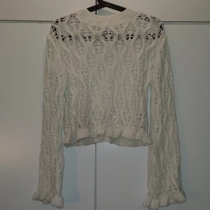 Vit stickad långärmad tröja - En vit stickad långärmad tröja. Stickad i ett mönster som kan kräva att ha en tröja under. Den sticks inte. Storlek S men passar de i M också. Den har använts en gång innan därav ingen prislapp kvar.