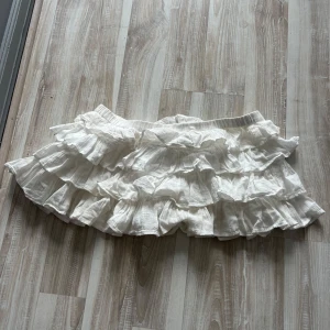 Lowwaist vit volangkjol med inbyggda shorts - Vit kort volangkjol med inbyggda shorts. Storlek L men sitter som S. Aldrig använda.