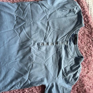 Ljusblå topp med knappar - Säljer en ljusblå topp från Zara. Den har korta ärmar och en rad med knappar framtill. Perfekt för en avslappnad stil!