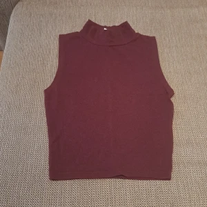 Vinröd ärmlös polotopp - Säljer en stilren vinröd topp som är ärmlös och perfekt för lager-på-lager-stil. Den är i ett mjukt material och har en tight passform som gör den både bekväm och snygg. Passar perfekt till både vardag och fest!