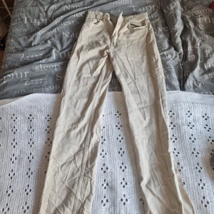 Beige byxor från FB Sister - Säljer ett par snygga beige byxor från FB Sister. De är i storlek S och har en klassisk design med dragkedja och knapp. Perfekta för en avslappnad stil eller vardagsbruk.