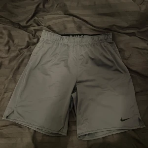 Grå träningsshorts från Nike - Snygga grå träningsshorts från Nike med elastisk midja. Perfekta för gymmet eller löprundan. Lätta och bekväma med bra passform. Storlek M använd 2-3 gånger