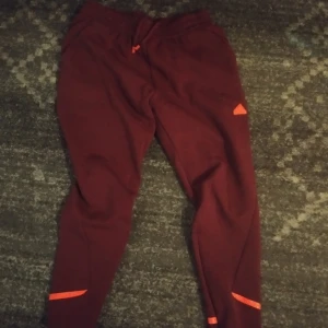 Vinröda med neon-orange  - Vinröda mjukisbyxor storlek XL (unisex)i nyskick, knappt använda och utan pilling eller defekter, tvättade en gång bara. Orange färgen är väldigt lysande. Typ neon-aktig Köptes alldeles nyligen för 849:- på adidas affären.