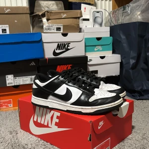 Nike Dunk i svart och vitt - Säljer ett par Nike Dunk i klassisk svart och vit färgkombination. Skorna har en stilren design med snörning och är i bra skick. Perfekta för både vardag och fest! Kommer med originalkartong. Pris diskuteras vid snabb affär