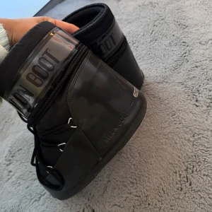Svarta Moon Boots - Säljer ett par klassiska svarta Moon Boots. De har en liten skrap repa där bak på ena skon men annars i bra skick
