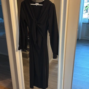 Svart långklänning med knyt vid brösten  - Elegant svart långklänning med knyt framtill och långa ärmar. Perfekt för jul/nyår/sommar. 