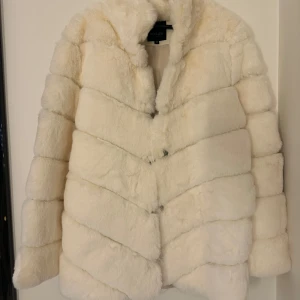 Vit pälsjacka från Hollies - Superfin vit pälsjacka från Hollies i storlek 36.               Fuskpäls, väldigt mjuk och fin. 100% polyester. Aldrig använd då den inte var min stil.  