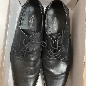 Svarta snörskor från Memphis One - Snygga svarta snörskor från Memphis One i skinn. Perfekta för både vardag och fest. Skorna har en klassisk design med rund tå och är i bra skick. Sulan är slitstark och ger bra grepp. Passar perfekt till kostym eller mer avslappnade outfits.