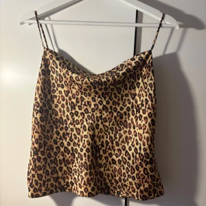 Leopardmönstrad linne i satin - Trendig leopardmönstrad linne i satin med smala axelband som dessutom har en fin guldkedjadetalj och som är justerbara. Inga tecken på användning och passar en S-M