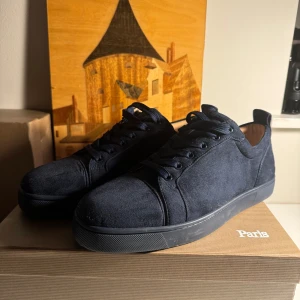 Marinblå Christian Louboutin - Säljer ett par stilrena marinblå sneakers i mocka. De har en klassisk design med snörning och en diskret logga på hälen. Perfekta för både vardag och fest! Skorna är i mycket bra skick och kommer i originalkartong.