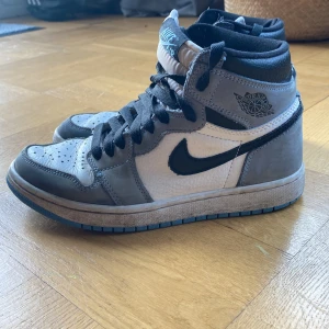 Nike Air Jordans i baby blue  - Snygga Nike Air Jordans i grått och svart med blå detaljer. Skorna har en hög modell med snörning och en klassisk Nike-logga på sidan. Perfekta för dig som vill ha en stilren och sportig look.