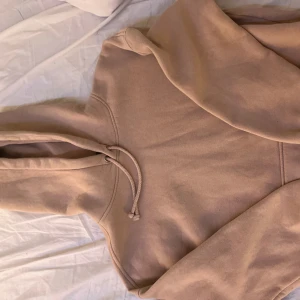 Beige hoodie från Bik Bok - Säljer en stilren beige hoodie från Bik Bok. Den har en klassisk design med en stor ficka framtill och justerbar huva med dragsko. Perfekt för en avslappnad look.