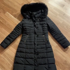 Svart dunjacka/vinterjacka från Armani Jeans - Snygg svart dunjacka från Armani Jeans med pälskantad huva i fuskpäls. Storlek 40 (italiensk) men motsvarar en 34. Precis kemtvättad. Knappen längst ner saknas men man använder bara dragkedjan. Dyr i inköp. 