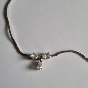 Elegant silverhalsband med droppformade stenar silver 835 - Säljer ett elegant halsband i silver med tre droppformade, klara stenar som hänger i mitten. Perfekt för att ge en touch av glamour till vilken outfit som helst. Halsbandet har en enkel och stilren design med en smidig låsning. Silver 835