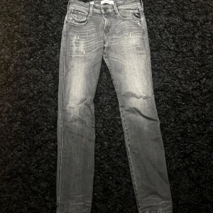 Replay Anbass  - Snygga grå jeansbyxor med en klassisk femficksdesign och diskreta slitningar. De har en normal passform och är perfekta för en avslappnad stil. Passar bra till både sneakers och kängor. Storlek 30W 34L