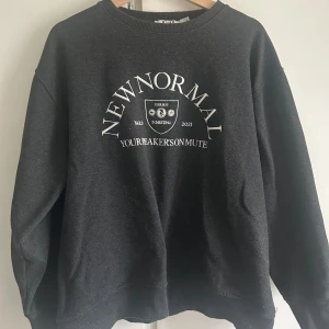 Svart sweatshirt från NA-KD - Säljer en svart sweatshirt från NA-KD i storlek S. Den har ett tryck med texten 'NEW NORMAL' och 'YOUR SPEAKER'S ON MUTE'. Perfekt för en avslappnad stil och passar bra till både jeans och leggings. Tröjan är i bra skick och superbekväm att ha på sig. Perfekt för höst och vinter!