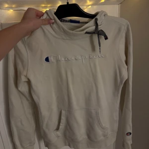 Vit hoodie från Champion - Säljer en vit hoodie från Champion. Perfekt för chilliga dagar eller som ett extra lager under jackan. Den är redo för nya äventyr! 🏆Storlek XS pris 200:-