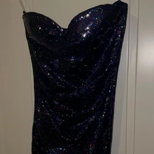 Mörkblå glittrig/ paljett klänning - Säljer en superfin marinblå klänning, helt oanvänd med massor av glitter som verkligen fångar ljuset. Den är axelbandslös, fast kommer även med band för extra support och perfekt för festliga tillfällen. Klänningen har en tight passform som framhäver figuren. Perfekt för nyår eller en utekväll! ✨Storleken är 32/34 och nypris är 998kr. Prislapp finns kvar! 