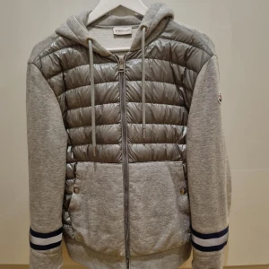 Grå Cardigan från Moncler (Unik Design) - Unik design på cardigan med patches på armarna där även QR kod funkar och certifierings intyg och kvitto finns, toppen skick förutom ett litet skrap märke vid dragkedjan längst ner. Perfekt för höst, vår, sommar rekommenderar inte till vinter. Storlek L men passar bättre som M för liten för mig som är 192.