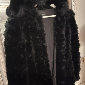 Svart pälsjacka från Zara - Säljer en supermjuk och elegant svart pälsjacka från Zara. Perfekt för vintern med sin fluffiga och varma design. Jackan har en klassisk stil och är i mycket bra skick. Den är långärmad och passar perfekt för både vardag och festliga tillfällen.