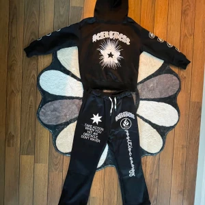 Egen-Designad Tracksuit - Helt ny och oanvänd. Tracksuiten var för liten på mig så en ny till migsjälv ska beställas. Denna tracksuiten är egen-designad, bra kvalitet och väldigt bekväm. Du får med båda byxor och hoodie vid köp. Streetwear mode är denna typ av stil. Byxorna är ”flared” så att benen kan få uttrymme att få luft.  Dressen kan KANSKE funka till någon med storlek S men största sannolik till någon med storlek XS.  Kontakta mig vid intresse.