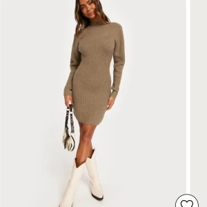 Beige stickad klänning - Snygg beige stickad klänning i ribbat material. Perfekt för höst och vinter med sin långa ärmar och kroppsnära passform. Klänningen är både stilren och bekväm, idealisk för både vardag och festligare tillfällen.