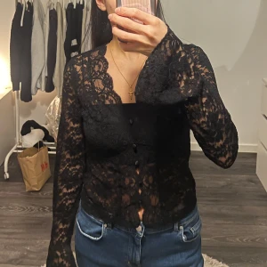 Svart spetsblus - Snygg svart spetsblus med långa ärmar och knappar framtill. Perfekt för en kväll ute eller en festlig tillställning. Blusen har en elegant och aldrig använd. Storlek S men passar även XS. Pris går att diskutera❤️