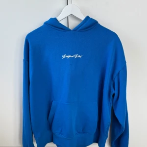 Blå hoodie från Redefined Rebel - Säljer en snygg blå hoodie från Redefined Rebel i storlek S. Använt den max 2 gånger.  Den har en klassisk design med en känguruficka och en liten logga på bröstet. Hyfsat stor i storleken. Pris kan diskuteras. Ordinarie pris 650kr