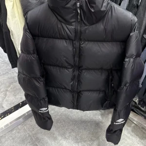 Svart dunjacka från Balenciaga - Säljer en snygg svart dunjacka från Balenciaga. Jackan har en pufferstil med dragkedja och långa ärmar. Perfekt för kalla dagar när du vill hålla dig varm och redo. Finns i alla storlekar skicka inget bud. Skriv bara sen därifrån rattar eran nya low key plug varor åt er. 